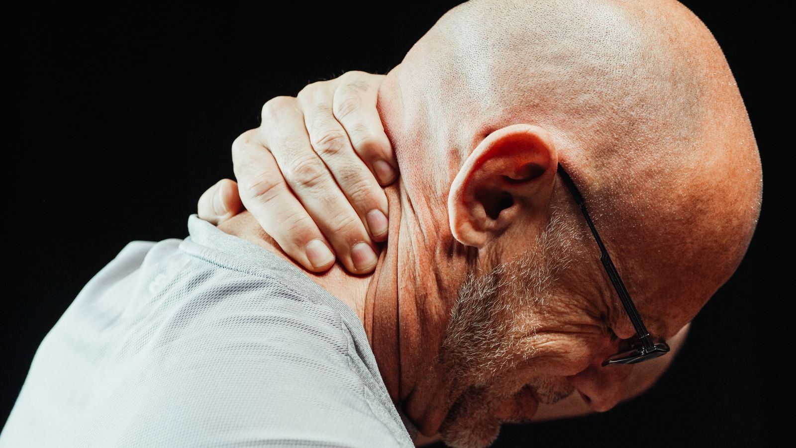 Person holding neck in pain, showing poor posture while using phone
