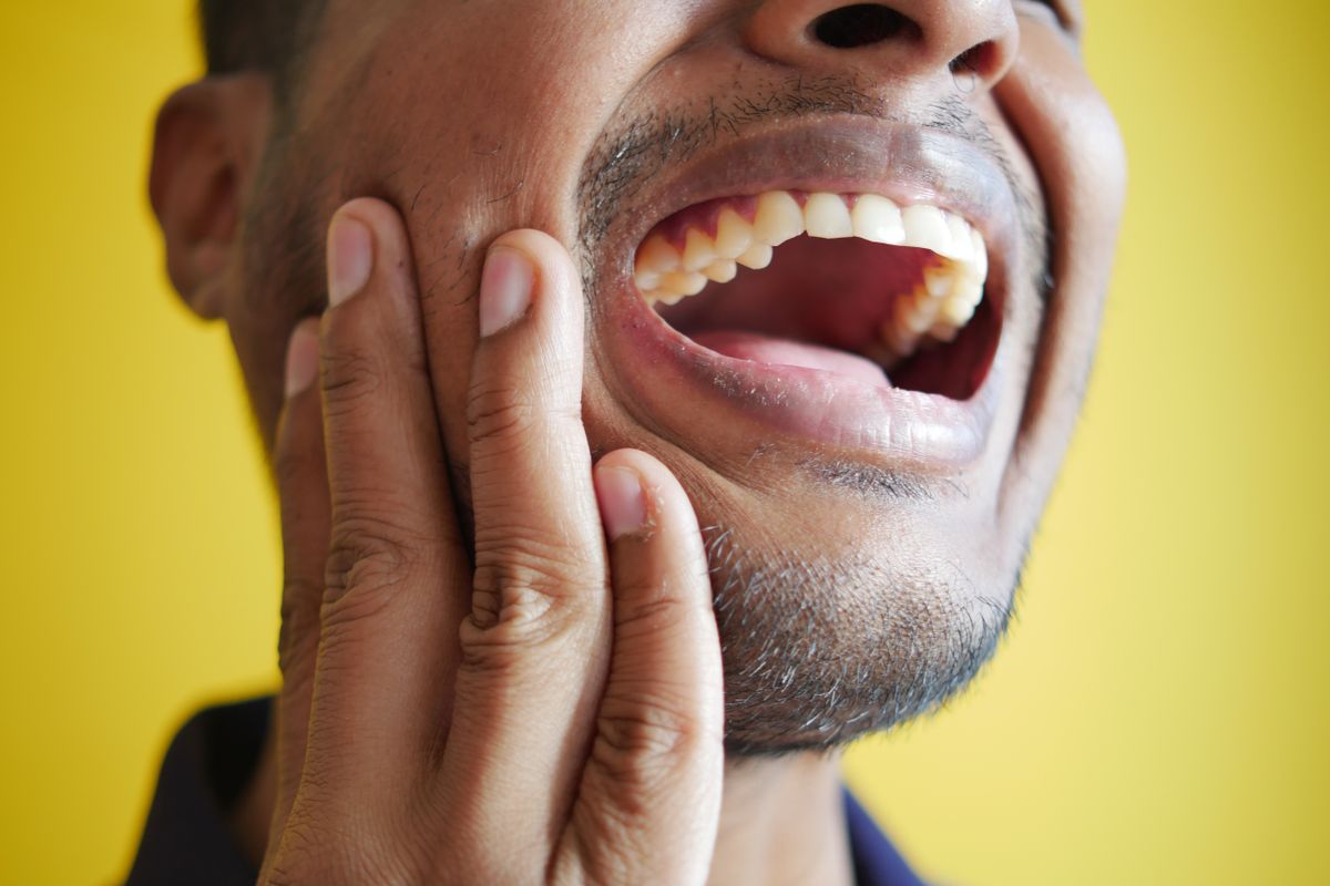 Person with toothache holding jaw — dental pain