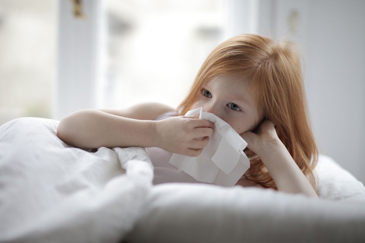 Sick child in bed with tissue — pediatric cold