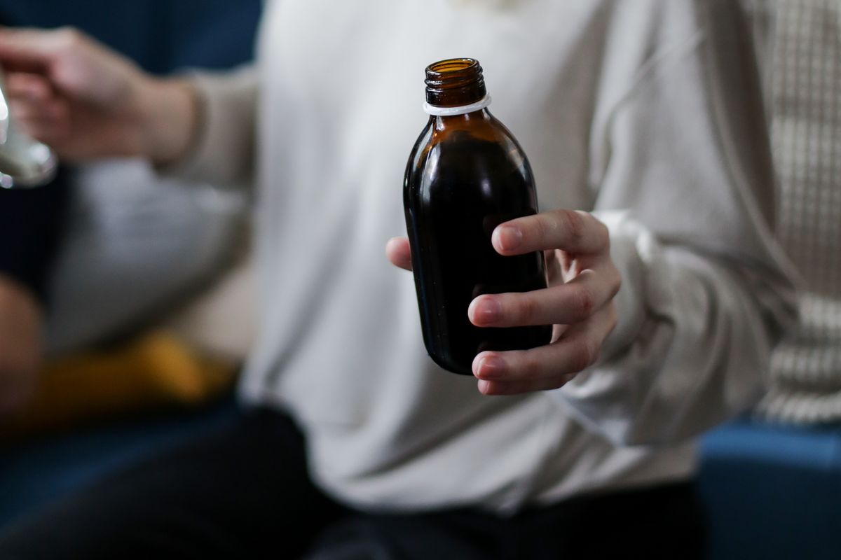 Hand holding amber medicine syrup bottle — Hydryllin